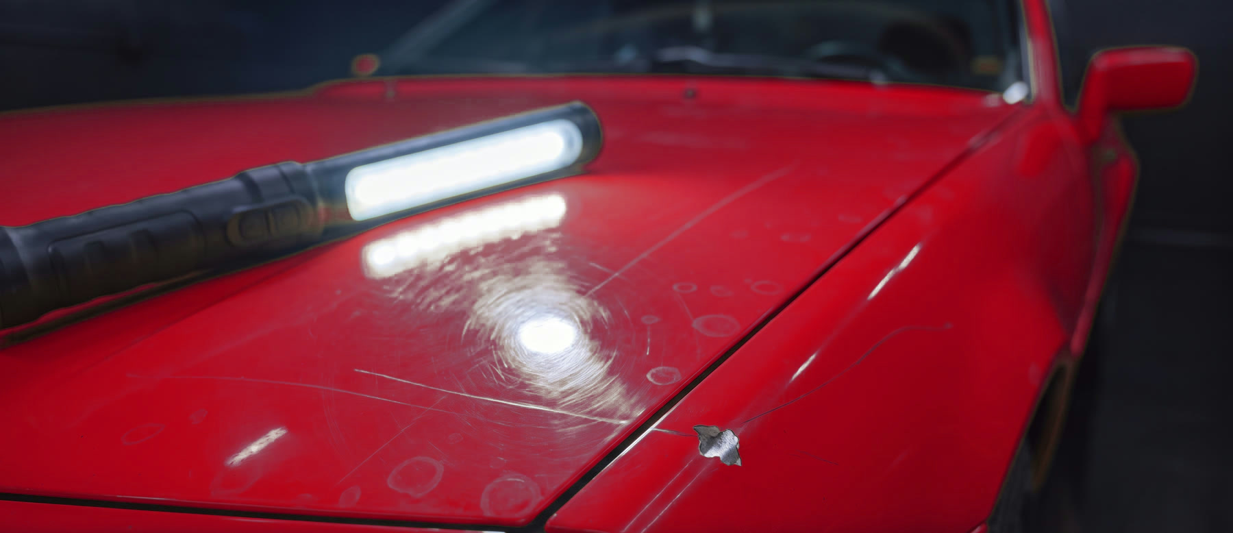 Close-up of paint under an inspection light showing swirl marks and scratches